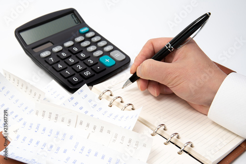 Hands of businessman writing a receipt on a notebook, close-up.