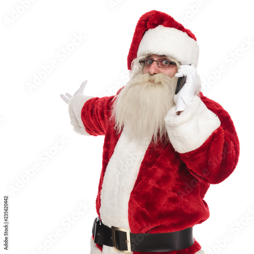 santa claus talking on the phone makes and inviting gesture