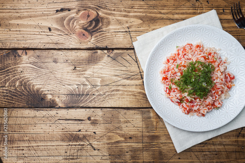 Rice with tomato sauce and greens on wooden background. Copy space