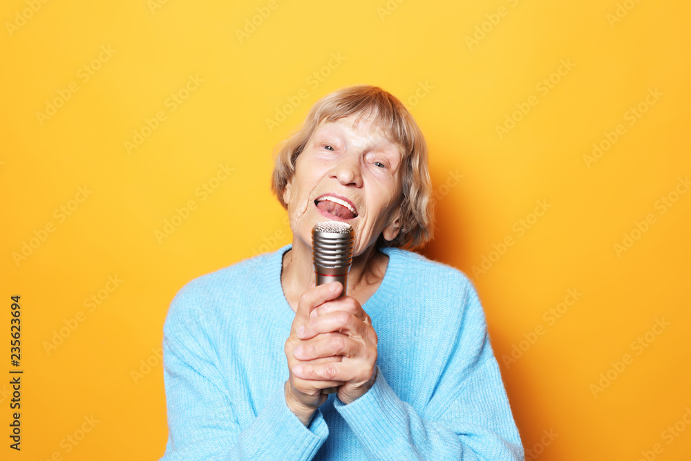 lifestyle and people concept: Happy old senior woman singing with microphone, having fun, expressing musical talent lifestyle and people concept: Happy old senior woman singing with microphone, having fun, expressing musical talent