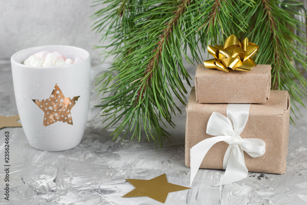 gift boxes, hot drink with marshmallows, shabby gray background with evergreen christmas tree branches gift boxes, hot drink with marshmallows, shabby gray background with evergreen christmas tree branches
