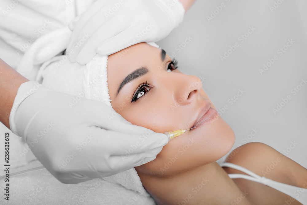 Beautiful woman having facial injection into area near mouth and nose ...