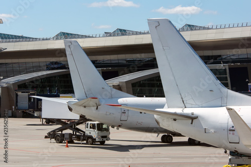 White modern twin engine civil airplane standing on parking place at ground maintenance at International airport.