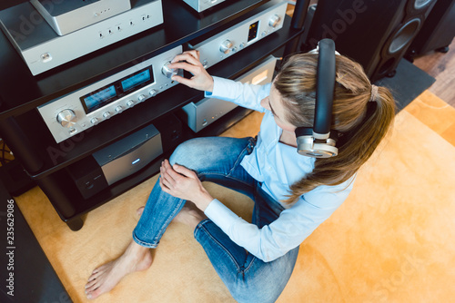 Woman with headphones listening to music via the Hi-Fi stereo in her home photo