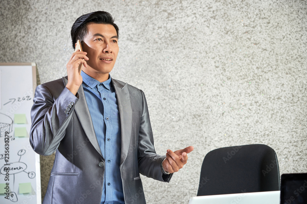 Φωτογραφία Asian mid adult businessman in beautiful suit standing at office and explaining