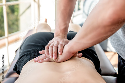 Therapist giving lower back sports massage to athlete male patient