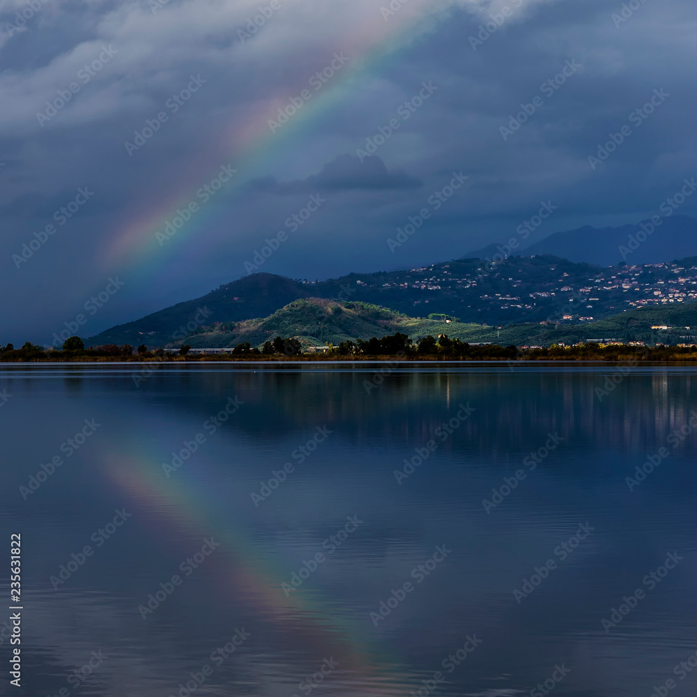The rainbow is reflected in the waters of Lake Massaciuccoli, Lucca, Tuscany, Italy