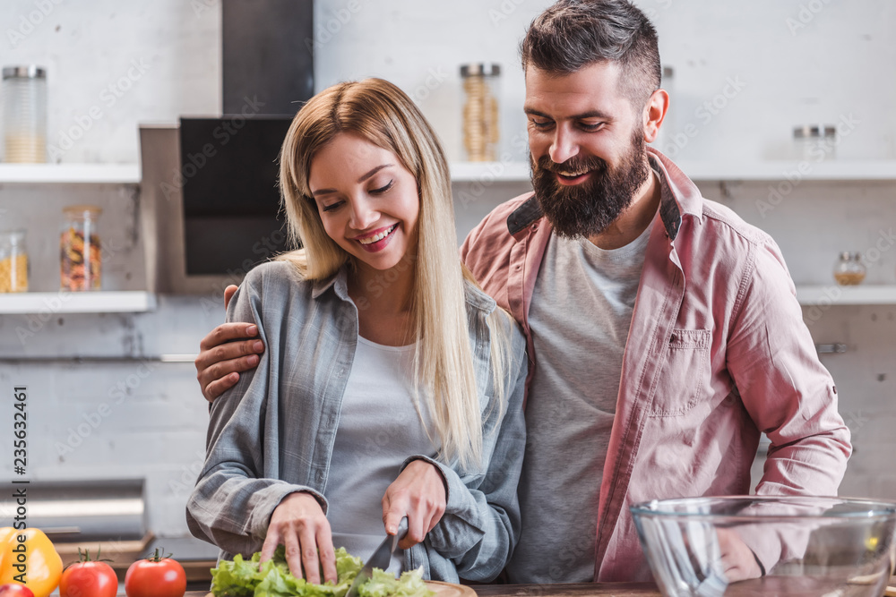 Smiling husband and wife preparing dinner in kitchen Smiling husband and wife preparing dinner in kitchen
