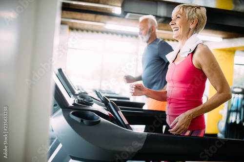 Senior people running in machine treadmill at fitness gym club photo