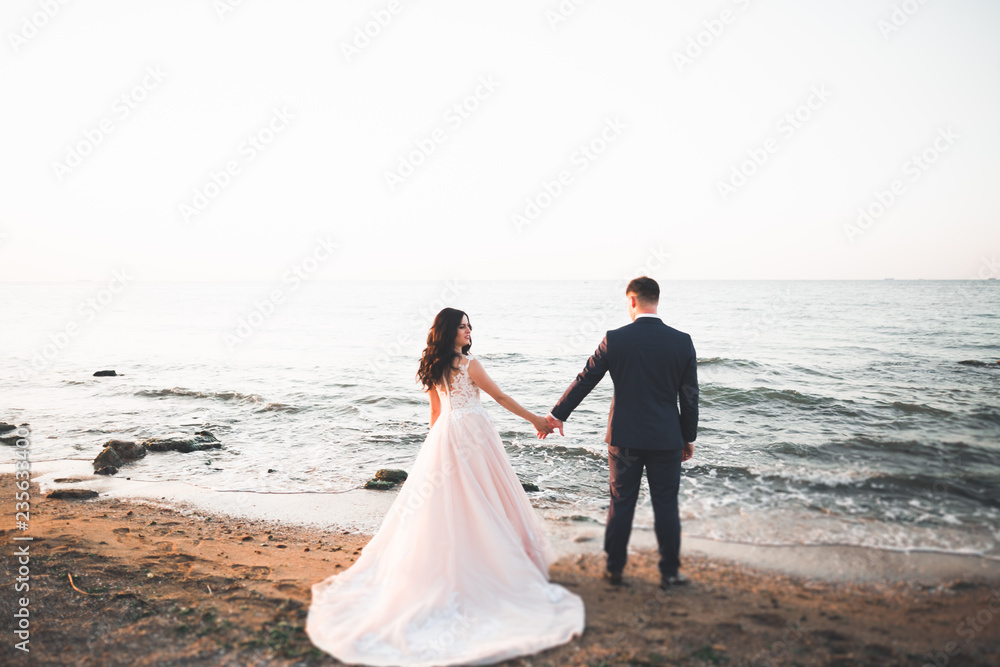 Wedding couple kissing and hugging on rocks near blue sea Wedding couple kissing and hugging on rocks near blue sea