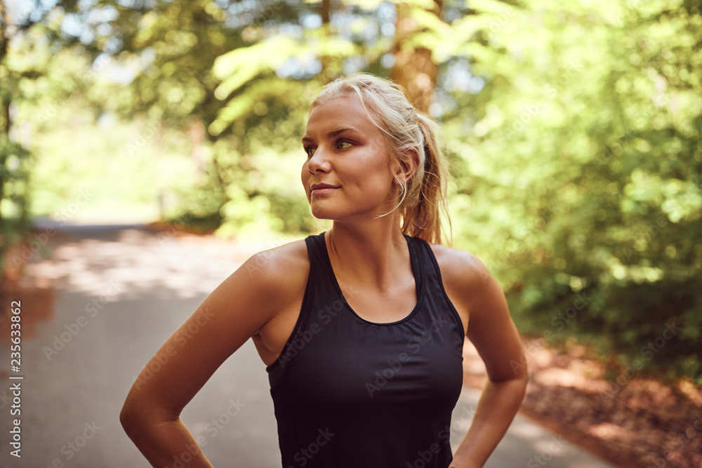 Fit young woman standing on a forest path before jogging Fit young woman standing on a forest path before jogging