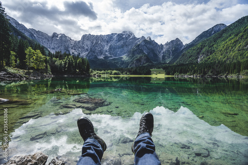 View of a mountain lake Lago Fusine, Julian alps and Tirol. Beautiful and clear alpine lake with blue and green colors, deep forest and high alpine peaks and rock faces.