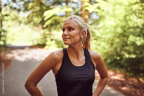 Fit young woman standing on a forest path before jogging