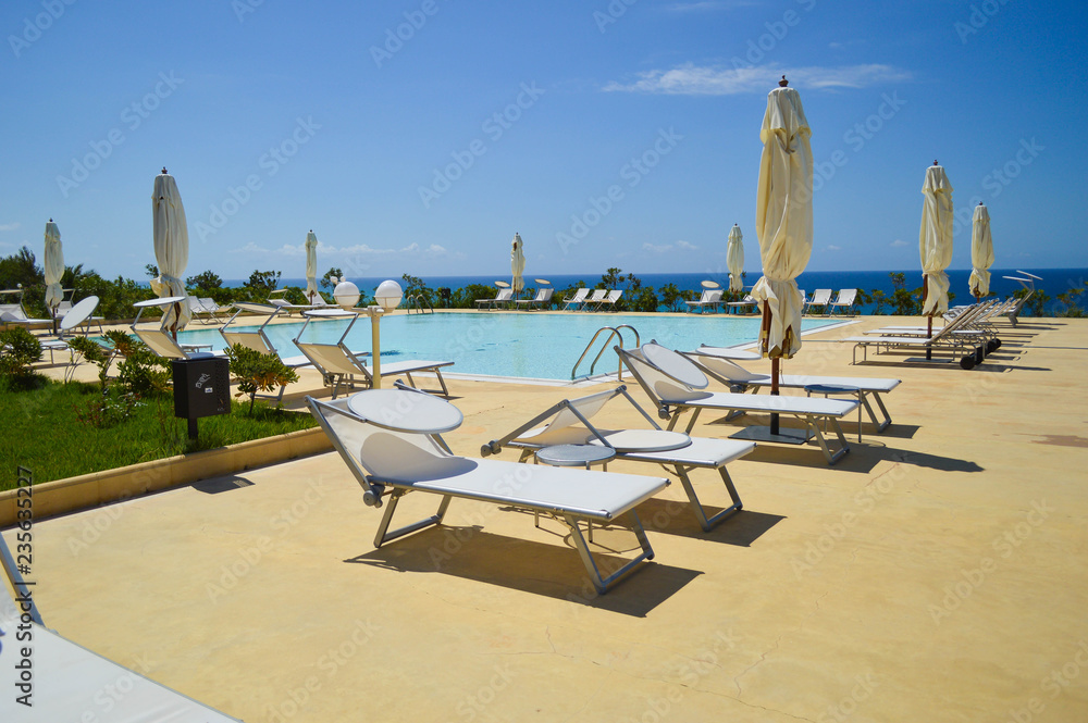 Obraz premium view of the pool in the hotel grounds with white sun loungers around