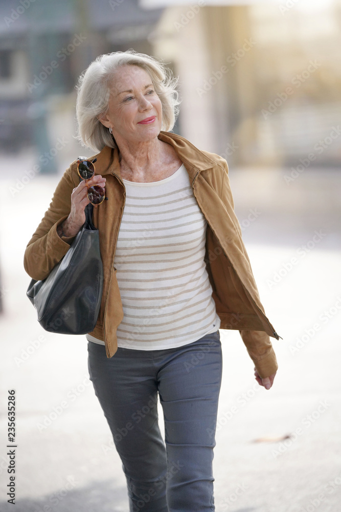 Fototapeta premium Attractive senior woman walking through town