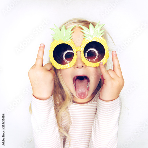 Cute little girl wearing pineapple glasses and making rude gestures