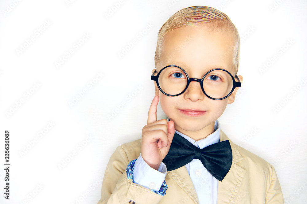 Smart little boy wearing glasses and a bowtie pointing upwards