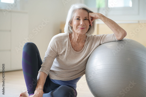  Smiling elderly woman resting on a swiss ball at home photo