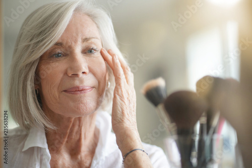 Attractive senior woman looking at herself in mirror photo