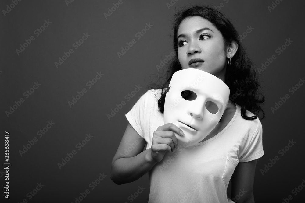 Portrait of young beautiful Asian woman holding mask Stock Photo