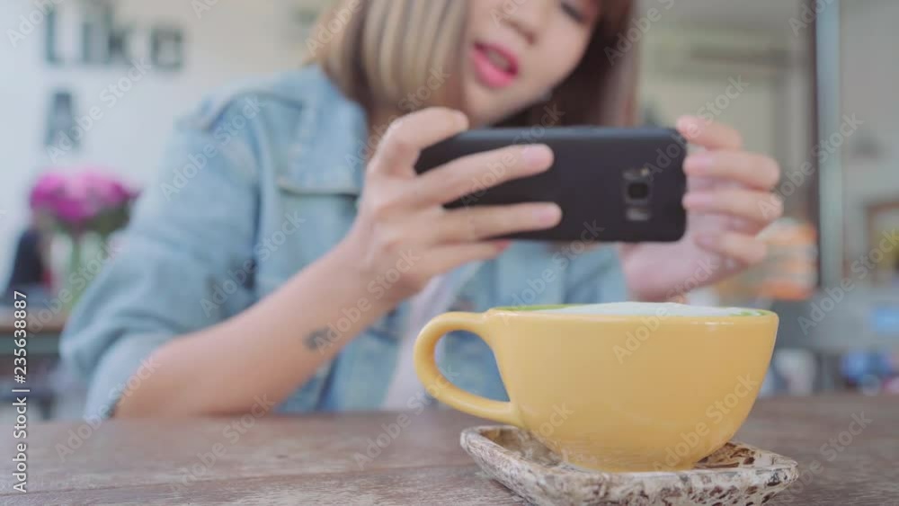 Female blogger photographing green tea cup in cafe with her phone. A young woman taking photo of coffee tea on smartphone, photographing meal with mobile camera.