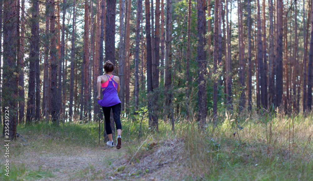 Obraz premium Young female runs in morning forest