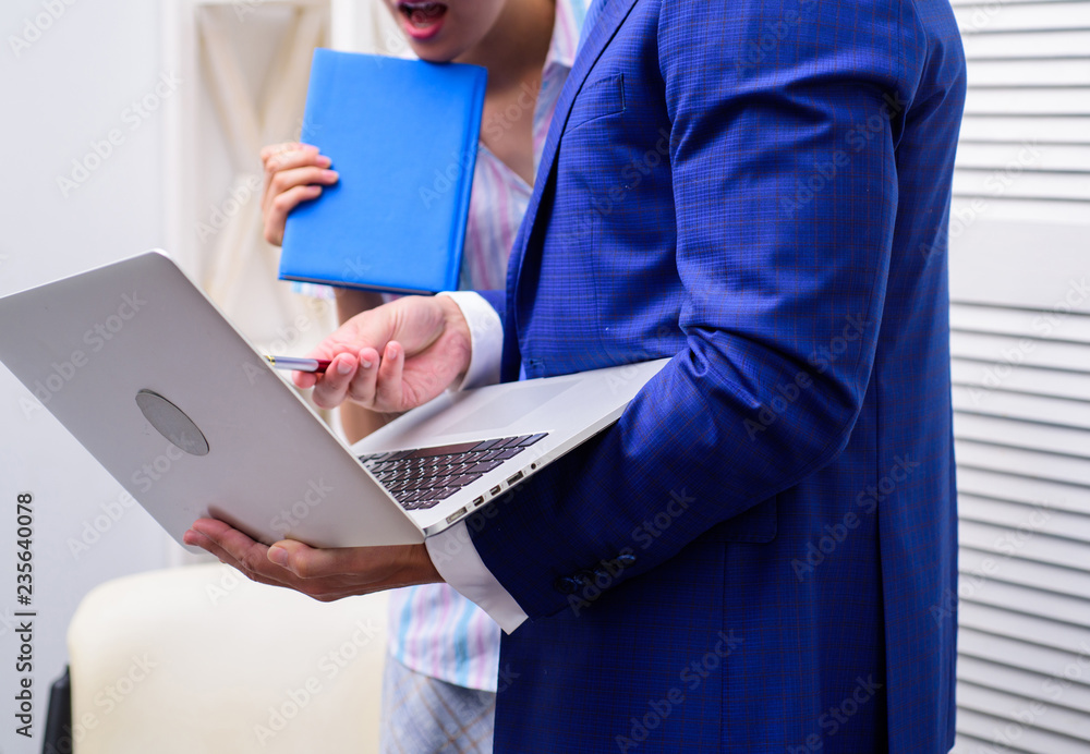 Work culture. Happy creative team working at office. Two joyful young people in formalwear holding laptop, book and discussing something while working together. Work culture. Happy creative team working at office. Two joyful young people in formalwear holding laptop, book and discussing something while working together.
