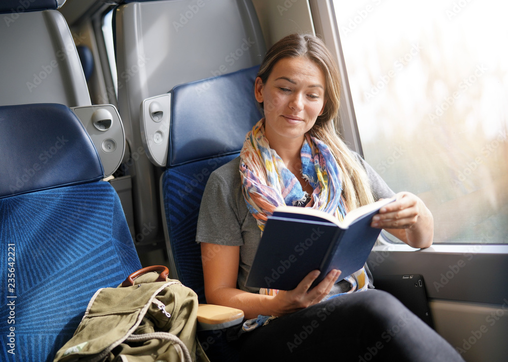 Relaxed young woman reading on the train