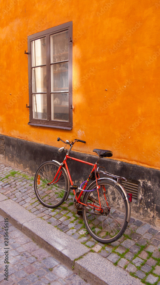 Red Bicycle on an Orange Wall on a cobblestone street in Stockholm, Sweden