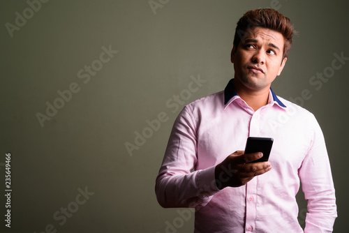 Indian businessman thinking and using mobile phone © Ranta Images