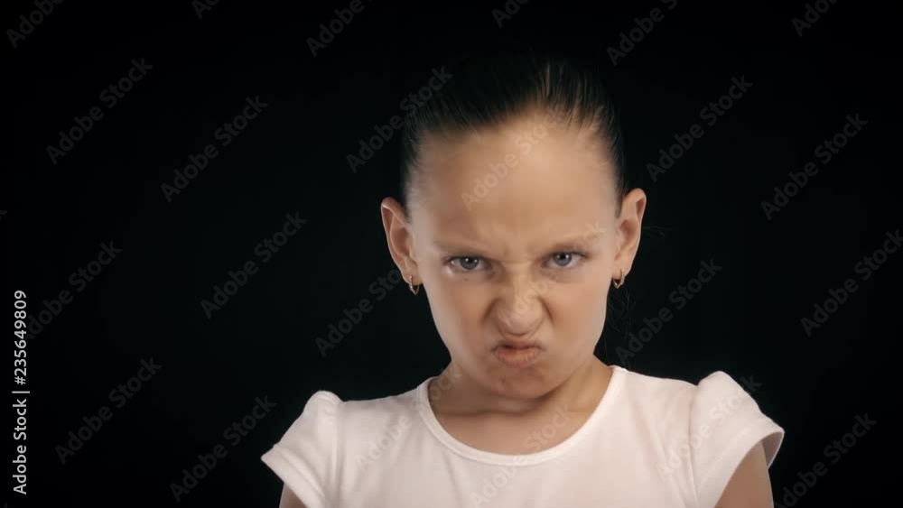 Portrait angry teenager girl clenched fists making kick with leg on black bacground Portrait angry teenager girl clenched fists making kick with leg on black bacground