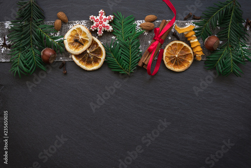 Frame with fir branches, Gingerbread cookies and Christmas decorations on dark stone background. Top view.