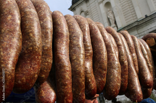 Raw stuffed sausages hanging on a street outdoor.