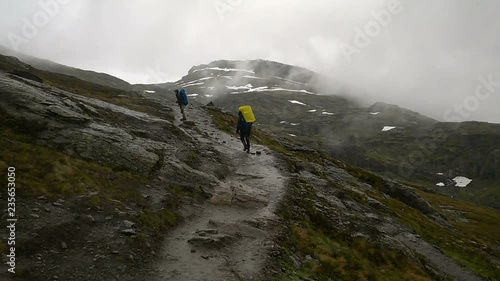 Tourists go on among the rocks. Path to the famous landmark - Trolltunga, Troll tongue. Hiking in Norway.