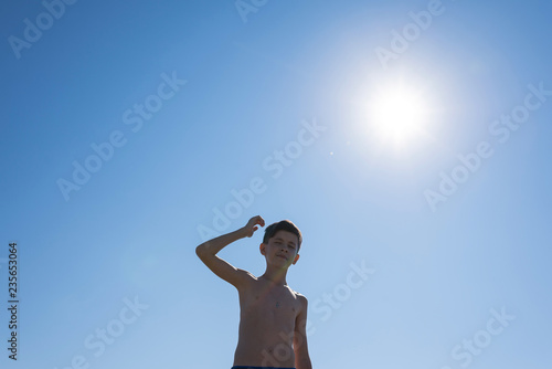 Silhouette of teen boy on the beach opposite sun. Concept