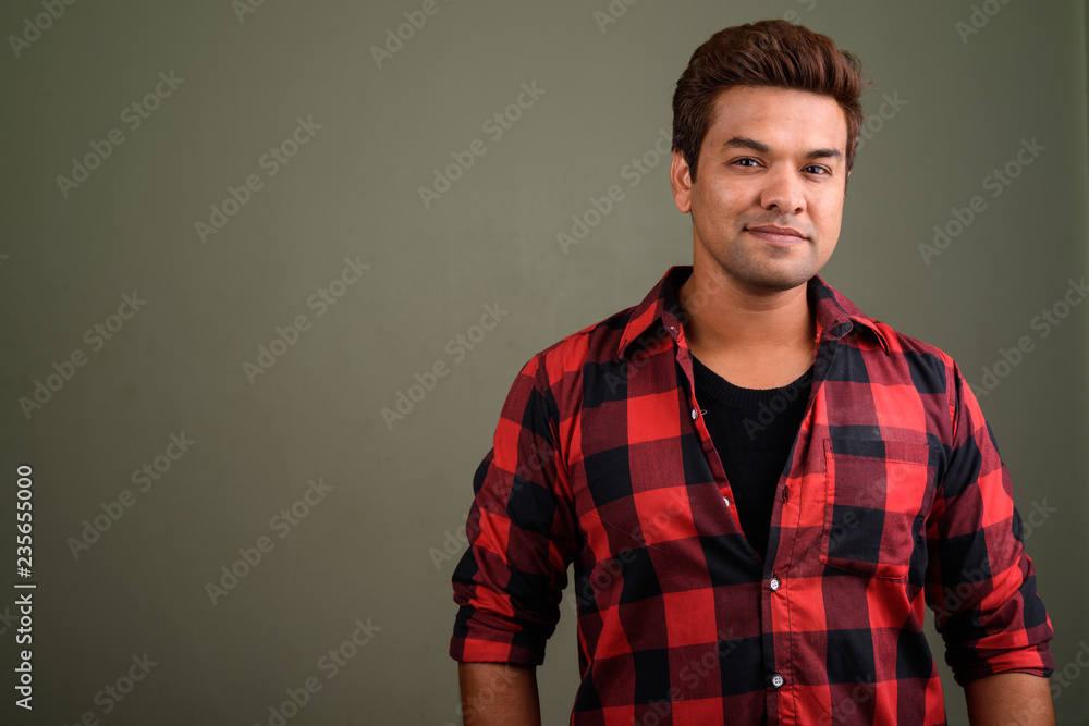 Fototapeta premium Indian man wearing red checkered shirt against colored backgroun