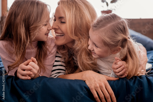 Excited woman laying on the bed with daughters