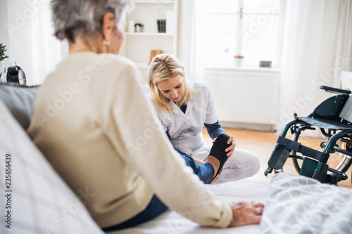 A health visitor putting on slippers on a senior woman at home. photo