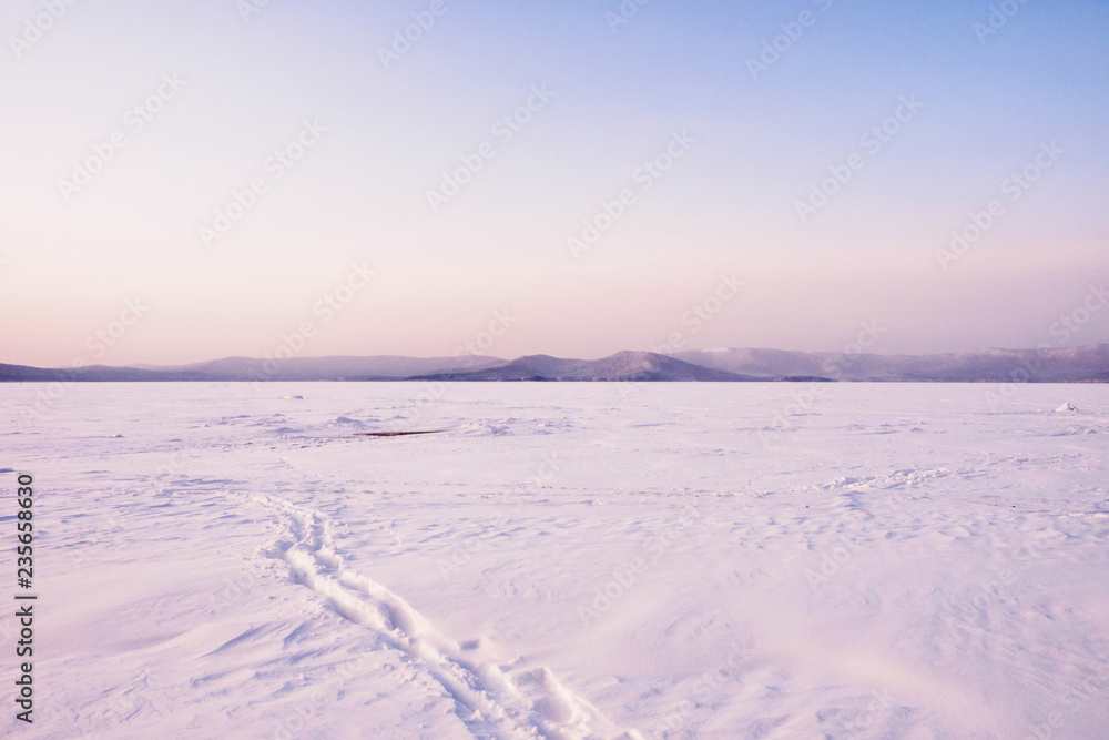 Winter landscape with trails in the snow. A path through the lake. Winter expanses during the twilight. Lake Turgoyak. South Ural. Russia. Winter landscape with trails in the snow. A path through the lake. Winter expanses during the twilight. Lake Turgoyak. South Ural. Russia.