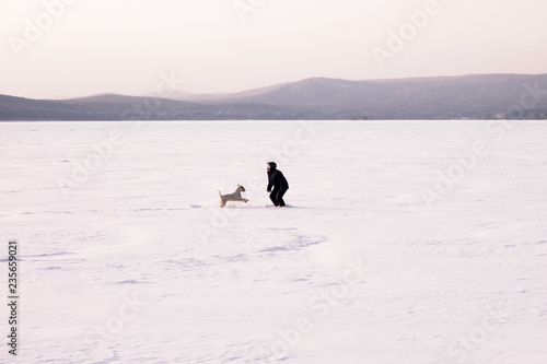 Women playing with the dog in the snowly winter. Natural Background. Frozen lake.