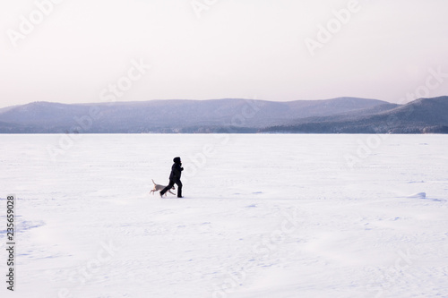 Women playing with the dog in the snowly winter. Natural Background. Frozen lake.