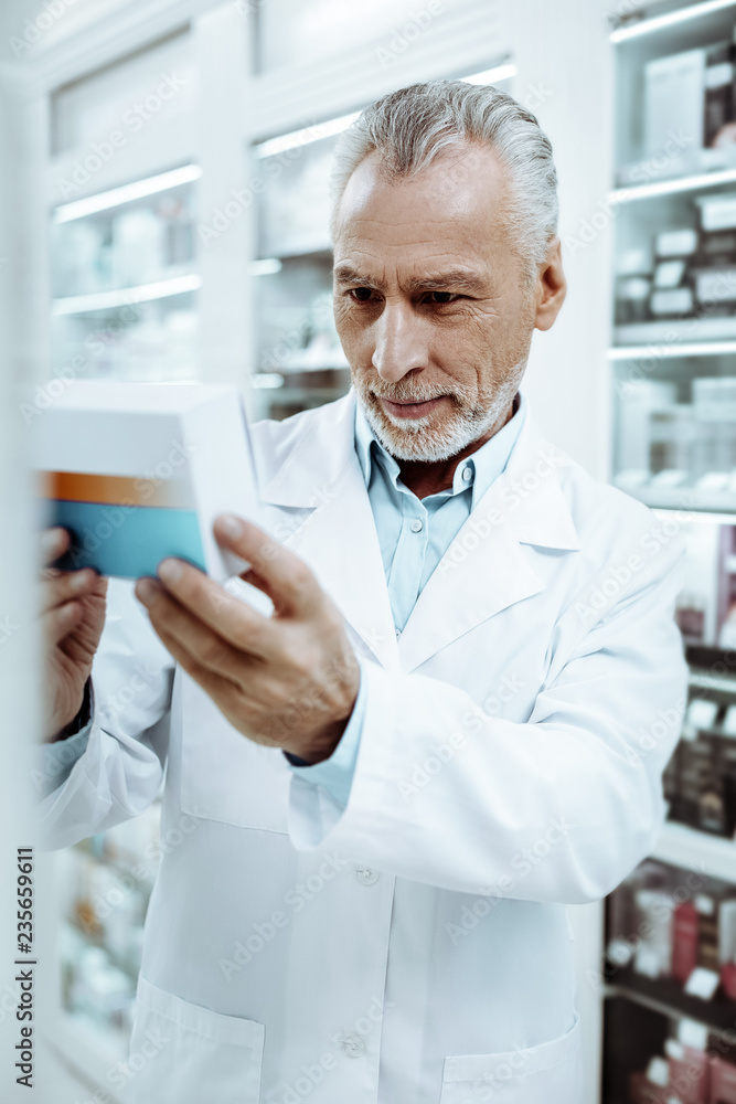 Concentrated mature man checking medicine before sale
