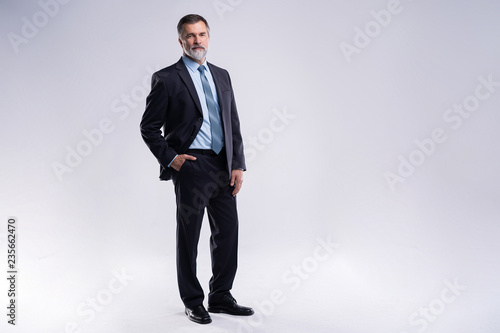 Fototapeta Full length portrait of confident mature businessman in formals standing isolated over white background.