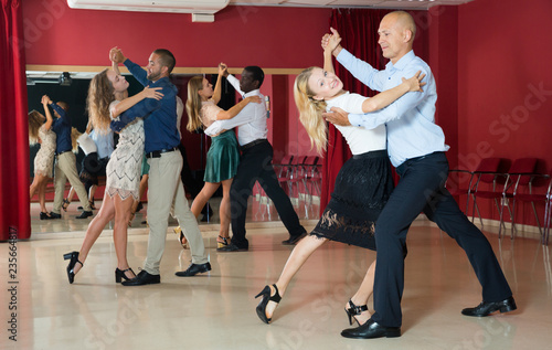 Positive adult couples dancing tango together in modern studio
