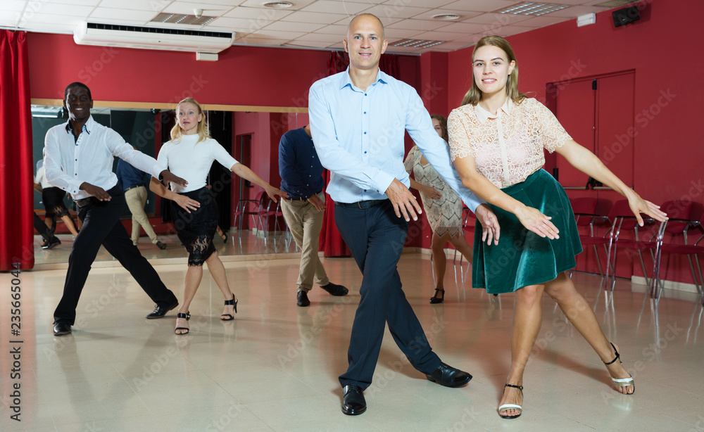 Active smiling people practicing  lindy hop movements in dance class