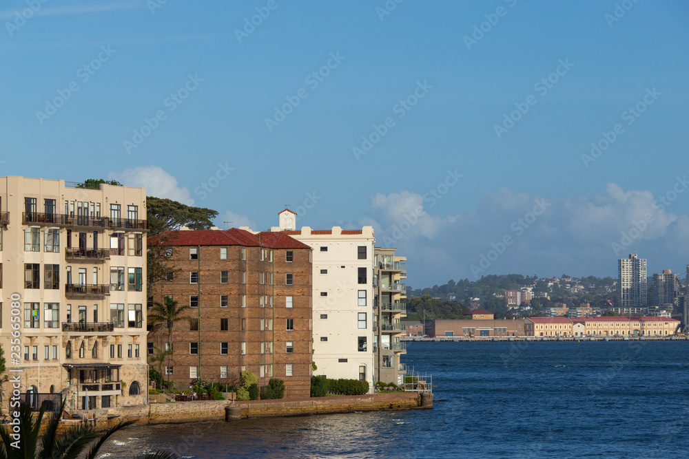 Apartment buildings by the water with clear blue sky.