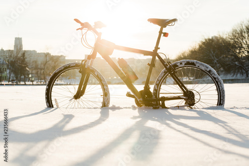 Winter season cycling. Black bicycle on the snow inte city center. Sport at any time of year concept. © beatleoff
