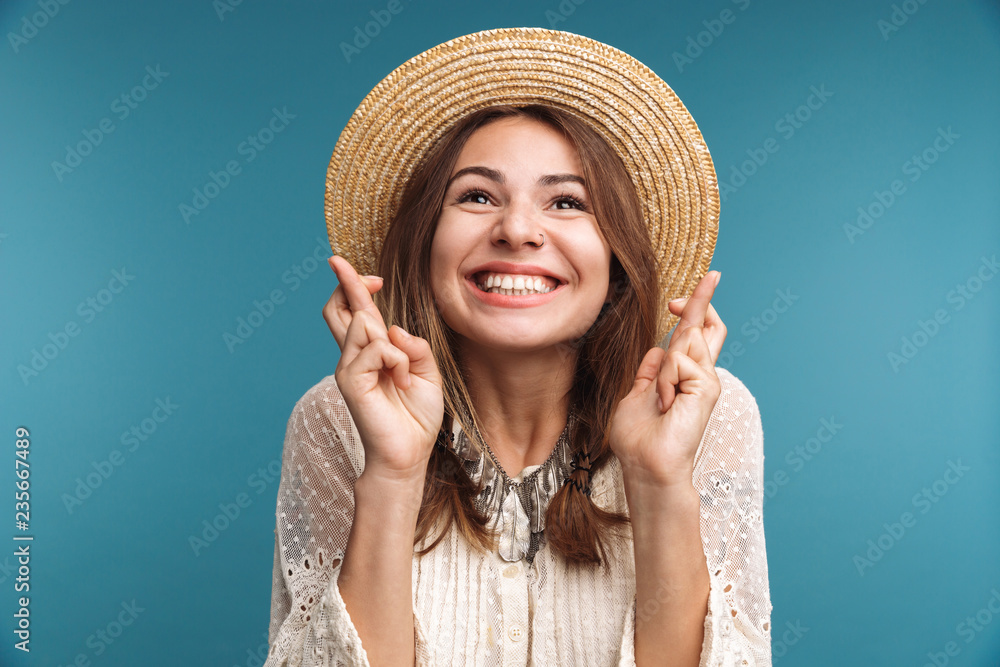 Happy pretty woman posing isolated over blue wall background showing hopeful gesture.