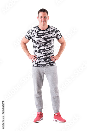 Relaxed young friendly handsome man smiling with arms on hips. Full body isolated on white background. 