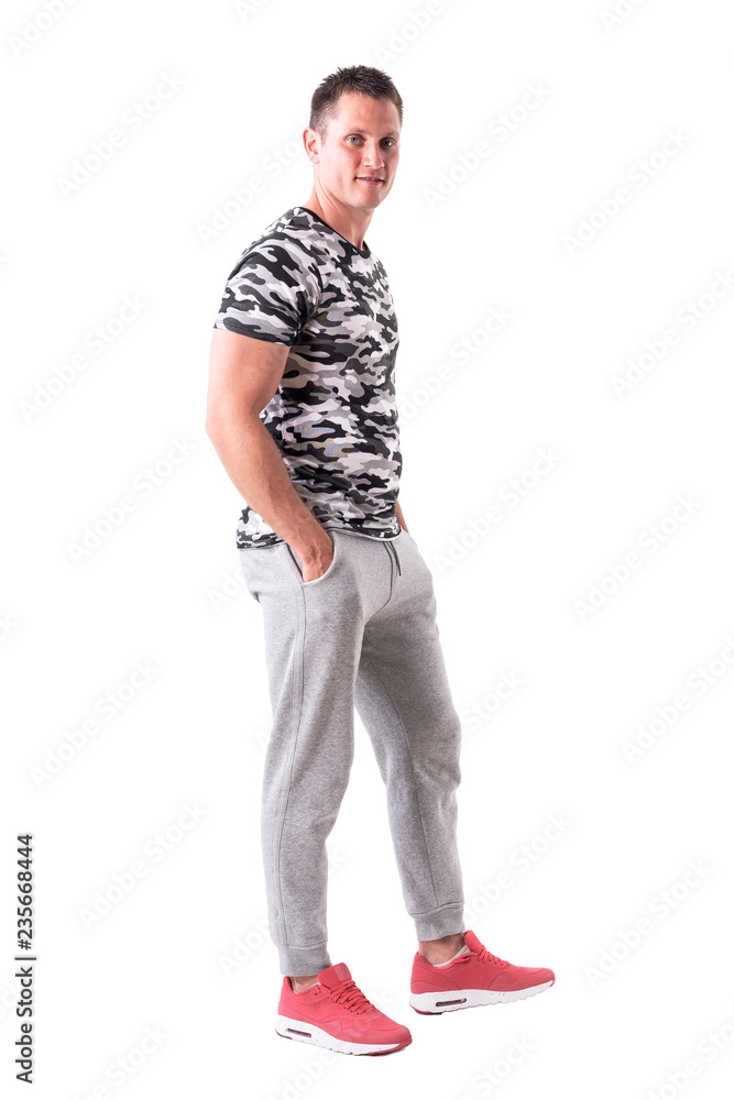 Confident happy handsome young adult man in sportswear with hands in pockets. Full body isolated on white background. Confident happy handsome young adult man in sportswear with hands in pockets. Full body isolated on white background.